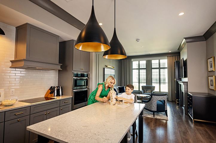 An internal room photo of a mother and son playing Jenga in the Kitchen at Hilton Club Liberty Place with the copy 'Charleston, South Carolina. Liberty Place'.