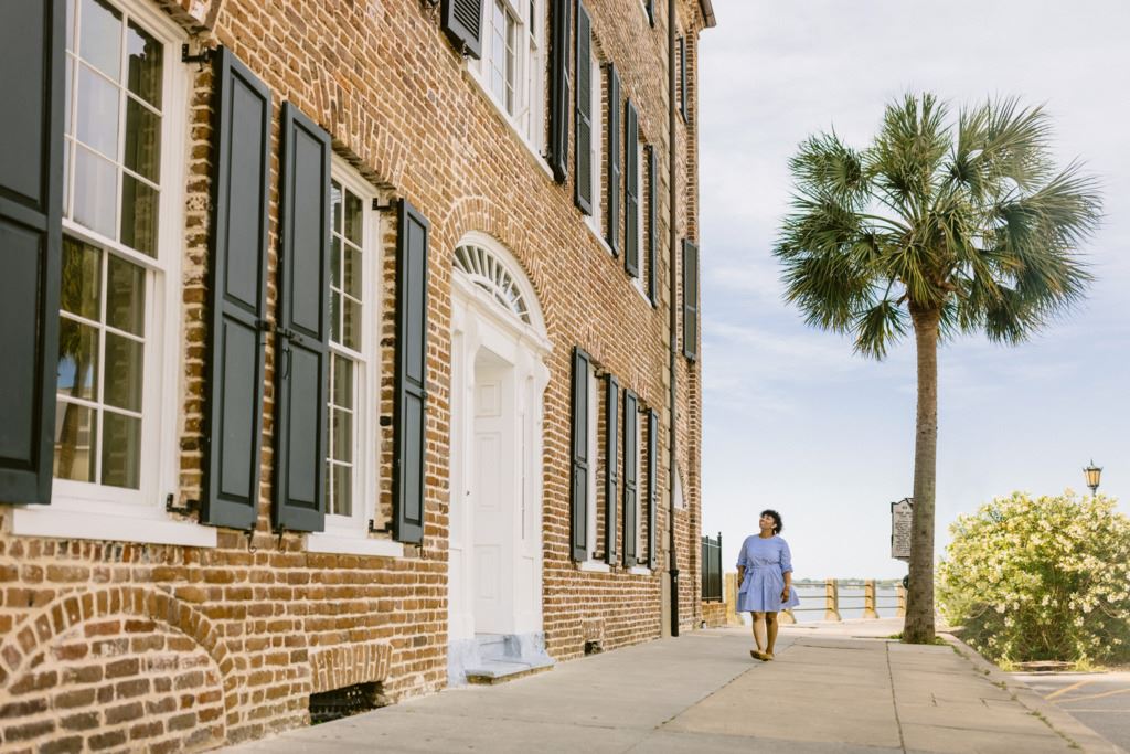 A woman walking by a traditional style Charleston building with a palm tree in the background and the copy '3-night getaway to Charleston'.
