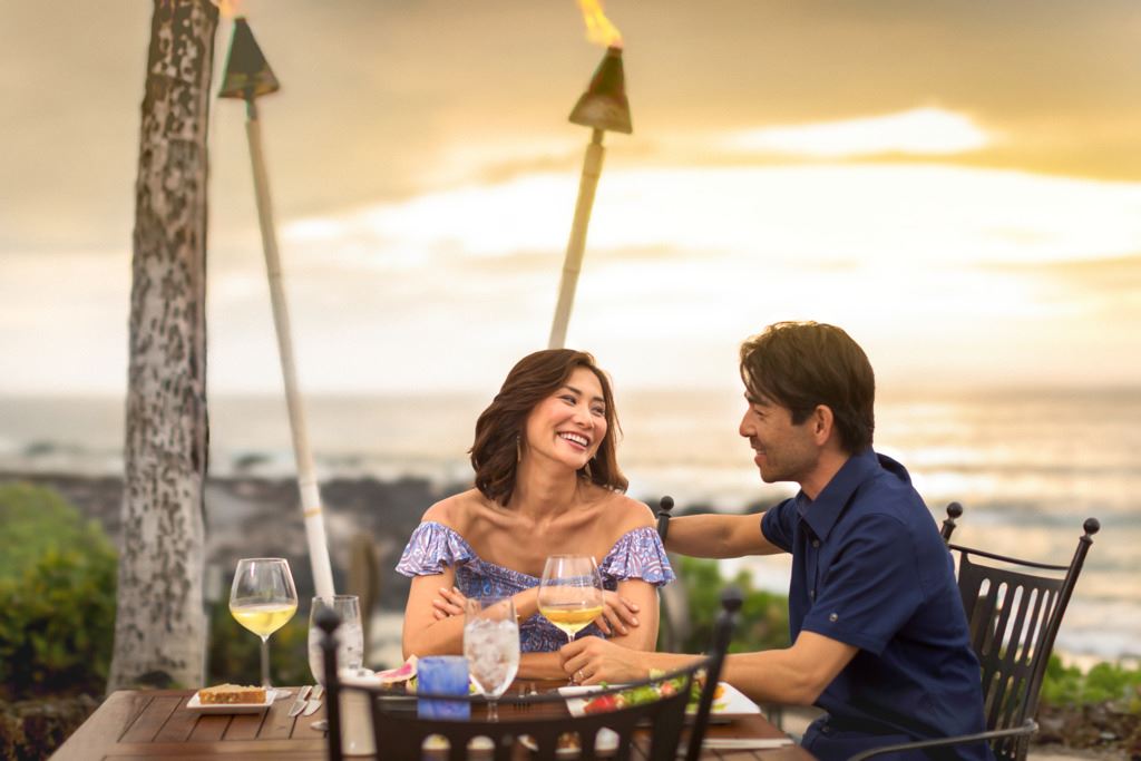Couple seated outdoors at sunset in Hawaii, Nevada, with the copy '8-night couples retreat Hawaii'.