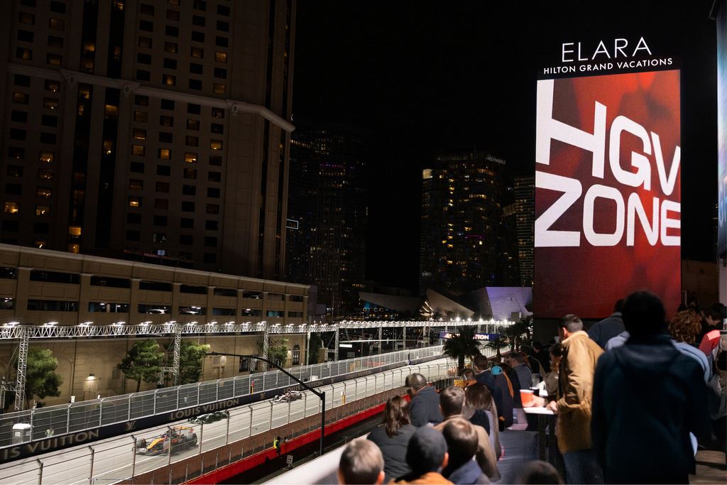 Crowd seated outdoors at night in Las Vegas, Nevada, with with the copy '4-Night Adventure to Las Vegas' and the Elara Hilton Grand Vacations in the background.&nbsp;&nbsp;